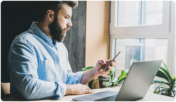 Man using his phone and laptop to contact business