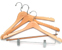 A small stack of two wooden clothes hangers with metal hooks lies on a white surface, positioned at a slight angle.