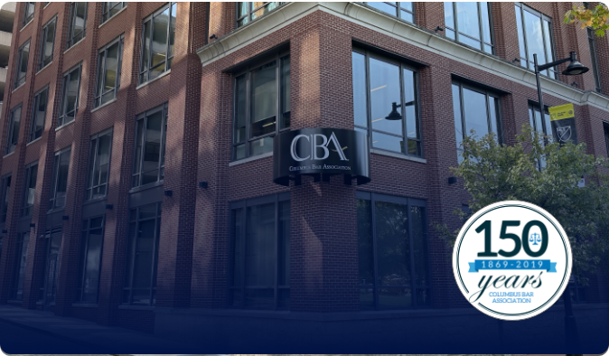 Brick building with a sign reading CBA for Columbus Bar Association. Logo in the corner: 150 years, 1869-2019, Columbus Bar Association. Building has large windows and street lamps nearby.